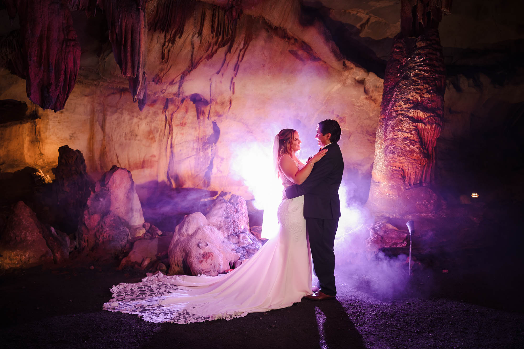 Wedding couple in dramatic cave setting with purple smoke lighting