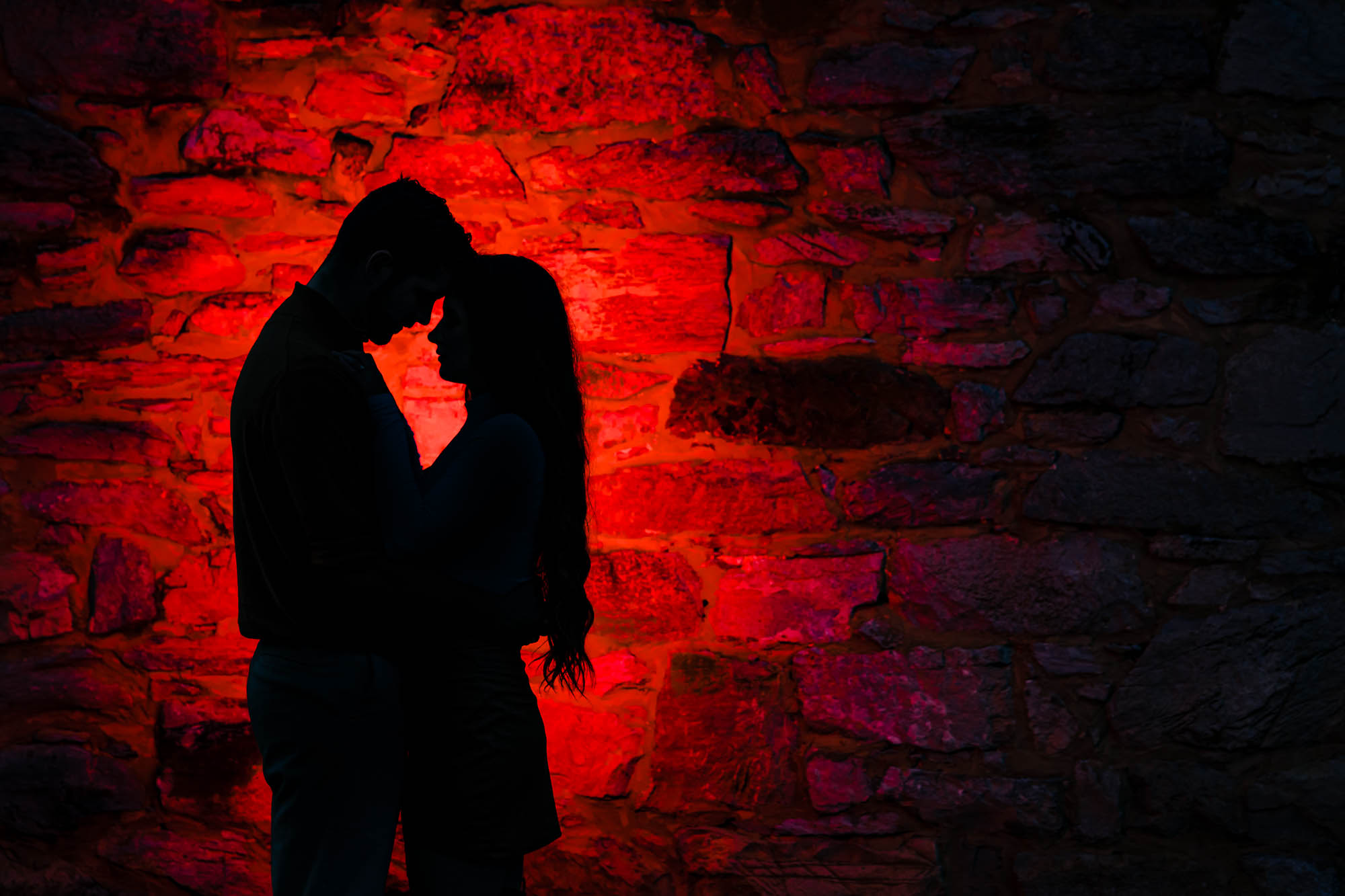 Couple silhouette against red lit stone wall
